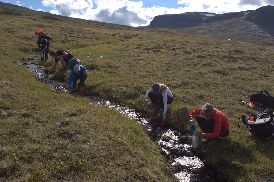 Refilling water bottles in a clean stream